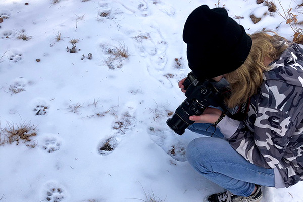 Teen taking photo in snow and animal tracks