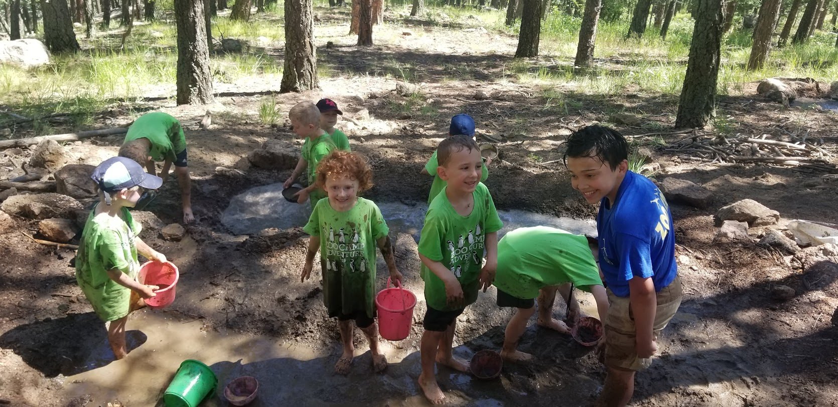 Summer campers kindergarten mud-kitchen fun in the mud outdoors together