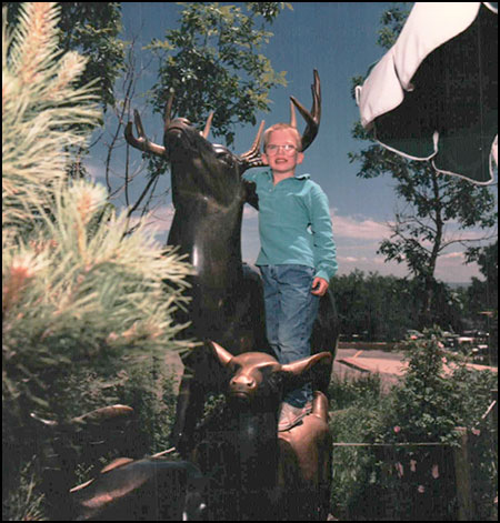 Boy guest on deer statue at Cheyenne Mountain Zoo