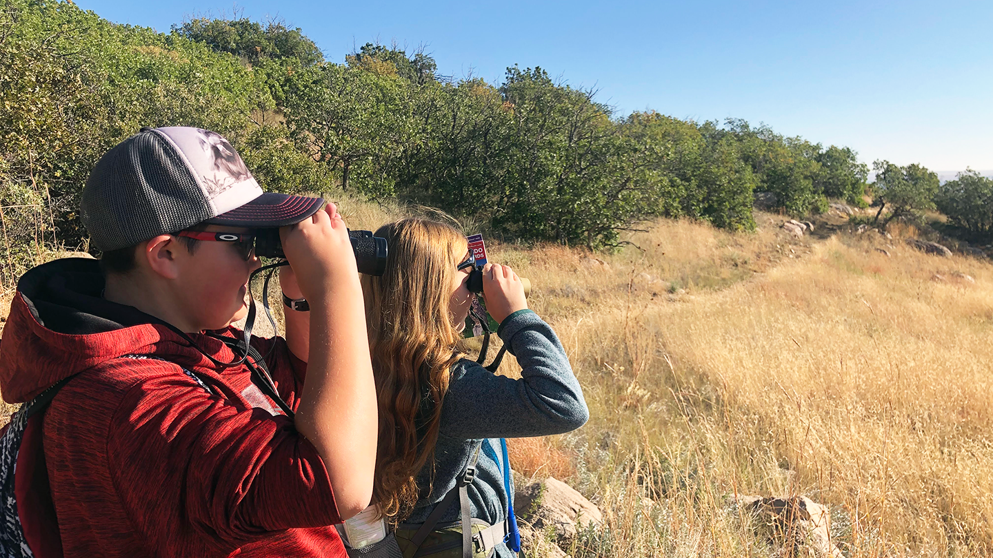 Teens spotting with binoculars in the wilderness